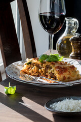 A serving of lasagna roll ups served with red wine garnished with basil.