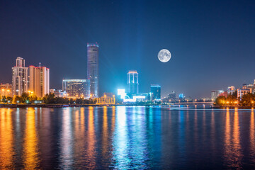 Night with big moon on a pond in the center of the city. Yekaterinburg city and pond at night.
