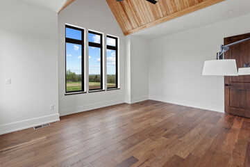 Empty bedroom with hardwood flooring and black windows