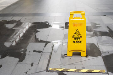 Yellow Caution slippery wet floor sign on the wet ground