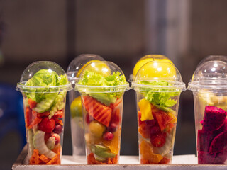 Assorted fruits and vegetables in clear plastic cups for make healthy smoothies.