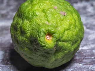 Close-up shot of whole  bergamot or kaffir lime fruit on the marble surface.