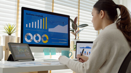 Young attractive asian thai woman employee busy work online multiple screen laptop computer or smart tablet at home in freelance sale data analytic, data science scientist engineer for business.