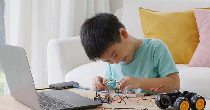 Asia people home school young small kid happy smile laugh self study online lesson excited make AI circuit toy. STEM STEAM digital class on laptop for active children play arduino enjoy fun hobby.