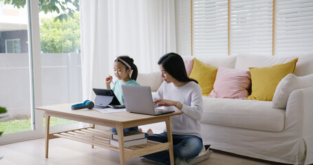 Adult asia people single mom small SME owner support happy sit busy apply child tax credit refund plan form app or pay loan bill on laptop. Little kid girl play at home hybrid job career workforce.