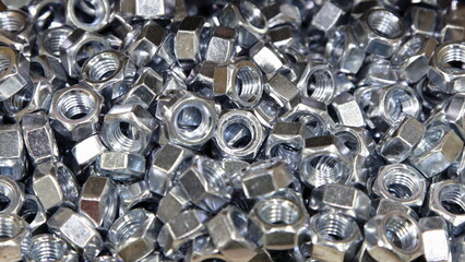 A lot of new gray shiny nuts. Galvanized construction fasteners. Industrial wide background texture.
