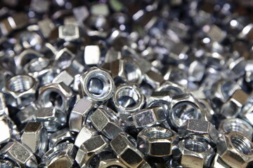A lot of new shiny grey nuts in perspective. Galvanized construction fasteners. Technical texture for the background.