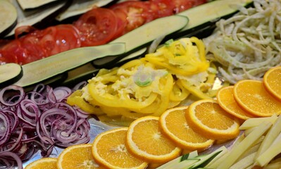 raw vegetables with onions peppers tomatoes aubergines and slices of fresh oranges in the kitchen of the industrial restaurant