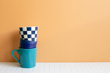 Stack of blue cups on white table. orange wall background. copy space