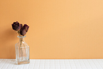 Vase of red dry rose flowers on white table. orange wall background. copy space