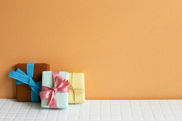 Colorful gift boxes on white table. orange wall background. copy space