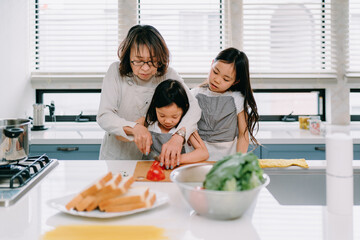 自宅で一緒に料理をしている祖母と孫娘たち