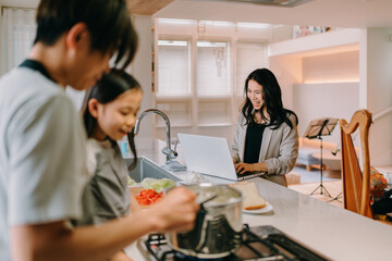 仕事をする母と食事の準備をする父と娘