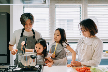 娘に料理を教える父親と見守る家族