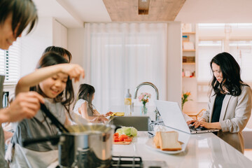 在宅勤務をする母と食事の準備をする父親と娘