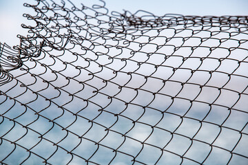 Metal netting against a background of the sea.
