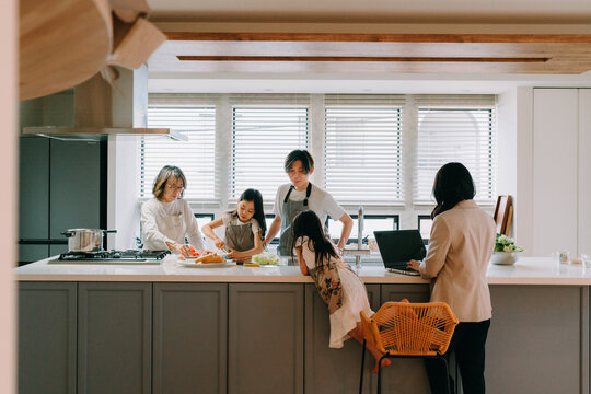 キッチンで食事の準備をする家族と働く母親