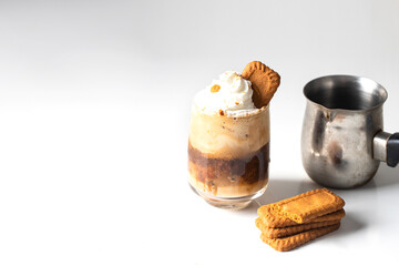 Cookies layered coffee glass with whipped cream  and decorated with biscuits on the  table .Close up