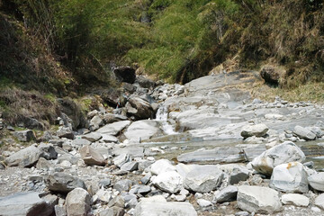 Natural rocky waterfall creek among green forest park