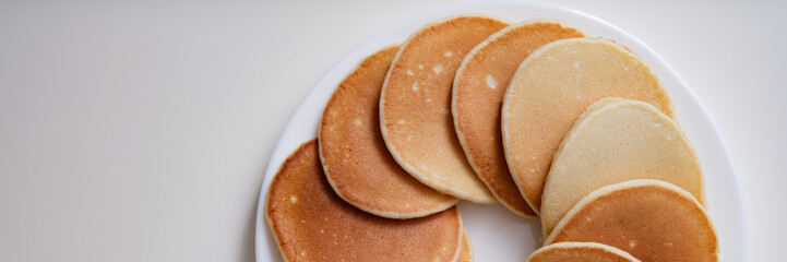 Lot of delicious appetizing pancakes lying on white plate in circle top view