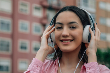 smiling young woman with headphones on the street