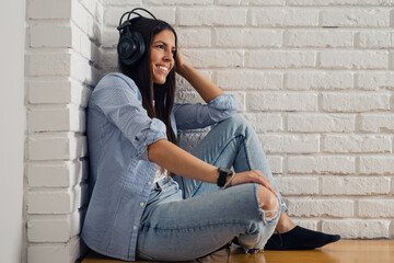 Fototapeta na wymiar Woman listening music in headphones in room