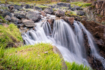 Obraz premium Summer polar landscape with waterfall in Teriberka. Kola Peninsula of the Barents Sea. The nature of the north of Russia