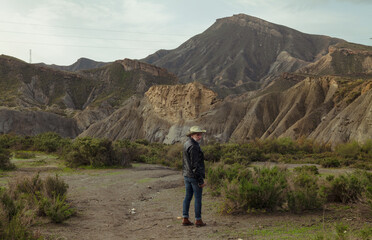 Fototapeta premium Rear view of adult man in cowboy hat in oasis of desert. Almeria, Spain