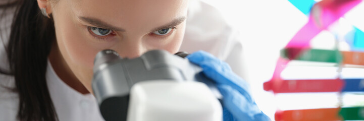 Woman scientist looking through a microscope, studying dna