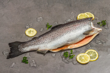Raw trout carcass with ice on a grey stone concrete background. Sea fish, healthy food