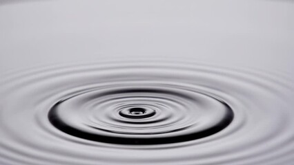 A single drop of water falling into a pool of water in slow motion. - Powered by Adobe