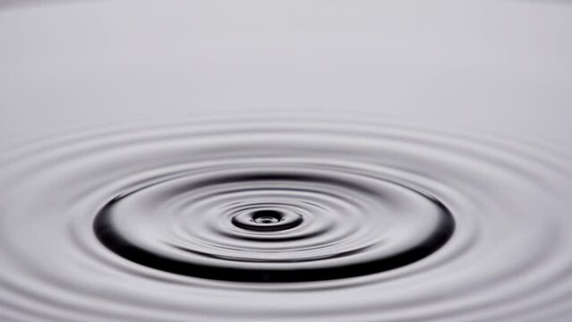 A single drop of water falling into a pool of water in slow motion.