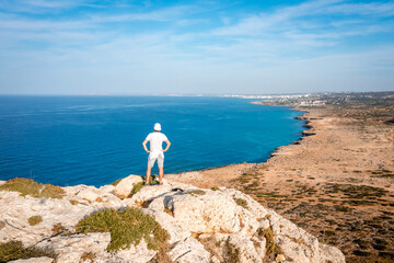 Summer landscape in Cyprus. View from the top of Cape Greco. Morning sunrise in Cyprus. A man stands on the edge of a cliff and admires the scenery