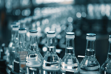 Closed glass bottles of upscale vodka transported by line