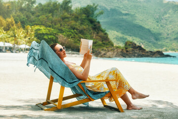  Woman reading book at beach resort during summer vacation.