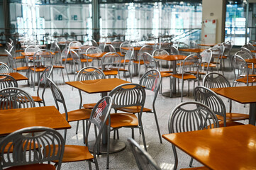 Wooden tables and chairs at large empty foodcourt in mall