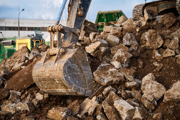 Fototapeta premium Bucket of excavator digs leftovers of destroyed building