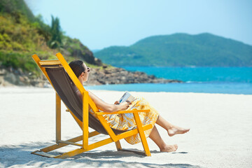 Woman reading book at beach resort during summer vacation. - 507217525
