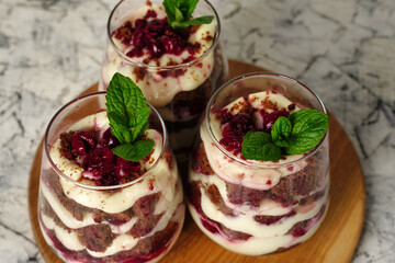 Sweet dessert with brown chocolate and white cream in a transparent glass. The cake is decorated with a mint leaf, birthday portioned cake.