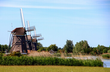 Three windmills in a row in Stompwijk on the Molenvaart in the Nieuwe Driemanspolder as a water management system