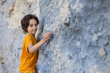 A little rock climber is training to climb a boulder