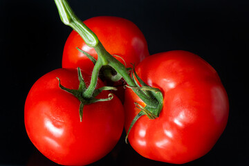 Red row ripe tomatoes with drops of water luminating. Fresh Appetizing natural antioxidants in tasty tomatoes. Heap of Tomatoes isolated on black background