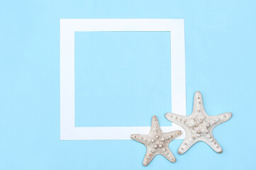 Fototapeta na wymiar White frame and starfish on a blue background