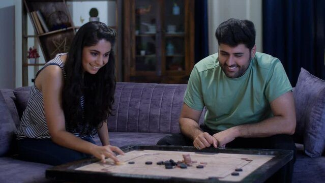 Attractive Indian husband-wife playing a game of carrom together - celebration  Indian couple. A young amazing couple spending quality time together - relationship and bonding  love and affection  ...