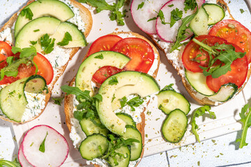 Toast with cream cheese or cottage cheese, with fresh vegetables - tomato, avocado, radish, cucumber, healthy diet spring sandwiches, Scandinavian toasts top view copy space