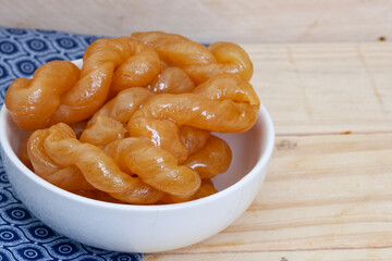 Delicious, golden, syrup drenched South African traditional koeksisters in a white bowl on rustic...