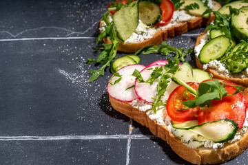 Toast with cream cheese or cottage cheese, with fresh vegetables - tomato, avocado, radish, cucumber, healthy diet spring sandwiches, Scandinavian toasts top view copy space