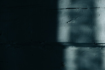 Gray uneven wooden log wall of rough texture with a moonlight from the window. Country style. Abstract background. Shadow and light. Natural old plank. Grey blue color. Moon night. Copy space. Cracks