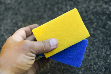 yellow and blue rectangular sponges in hand