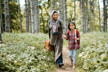 Happy Muslim mother and daughter going on picnic in forest. - Powered by Adobe
